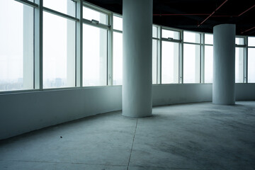 Naklejka premium Empty modern office space with floor-to-ceiling windows and concrete columns