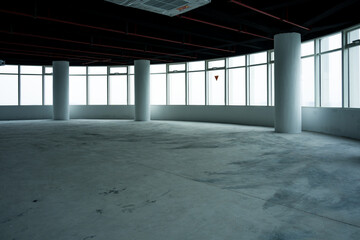 Naklejka premium Spacious industrial-style office space with unfinished concrete floor and exposed structural elements