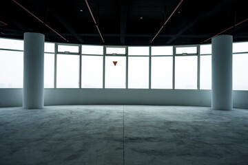 Naklejka premium Spacious empty office with floor-to-ceiling windows and concrete flooring