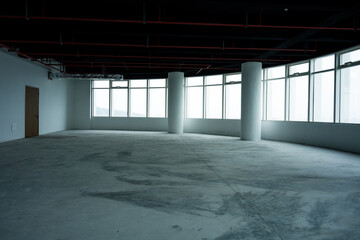 Naklejka premium Empty unfinished office interior space with concrete floor columns and large windows