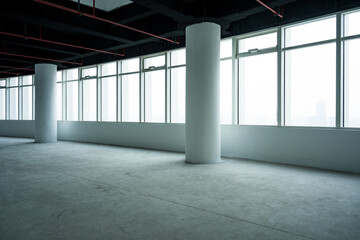 Naklejka premium Spacious office interior with white columns and large floor-to-ceiling windows