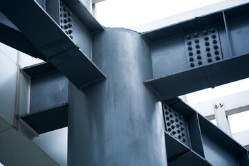 Naklejka premium Close-up of steel structural column intersecting with riveted cross beams at joint node