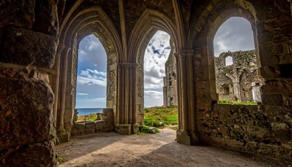 Obraz premium A stone arched building, its walls weathered, frames a sea vista. Through openings, a partial exterior view is presented, with clouds