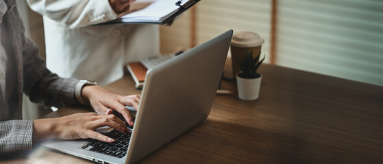 Businesswomen analyzing statistical reports on laptop at co working space in the office