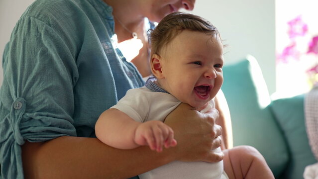 Mother holding baby during sneeze, infant reacting with scrunched face, moment of natural reflex, early childhood development, nurturing care, family warmth in cozy home