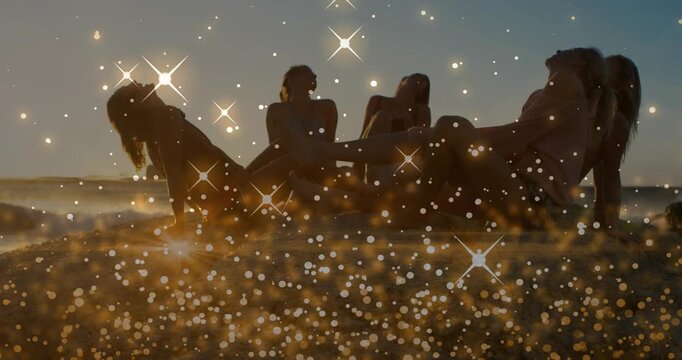 Five women reclining on sunset beach, sunset driving motion while golden bokeh overlaying marketing