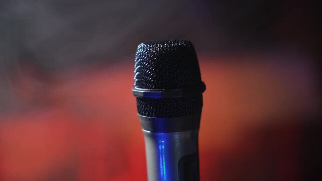 Studio microphone in atmospheric blue lighting with abstract stage background. Perfect for music recording, performance or podcast themes.