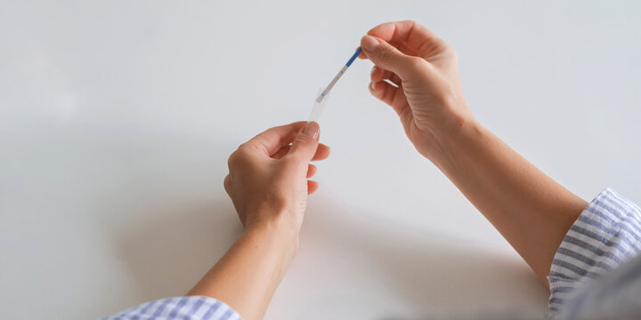 At-home rapid test kit, hands collecting nasal swab sample into tube, self testing, medical diagnostics, infection screening, telehealth concept, copy space.