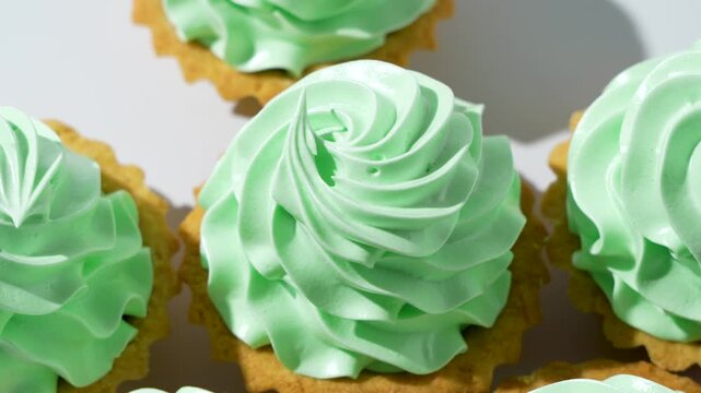 Minimalist rotating dessert shot of pastry tartlet topped with mint green cream swirl. Studio lighting highlights the texture and bakery detail.