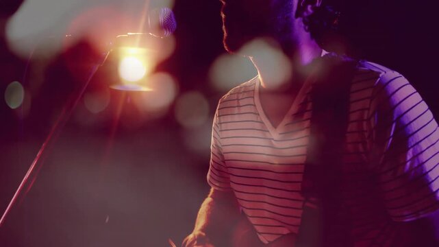 Musician starting to strum guitar, turning to mic; warm backlight and bokeh boosting music visuals