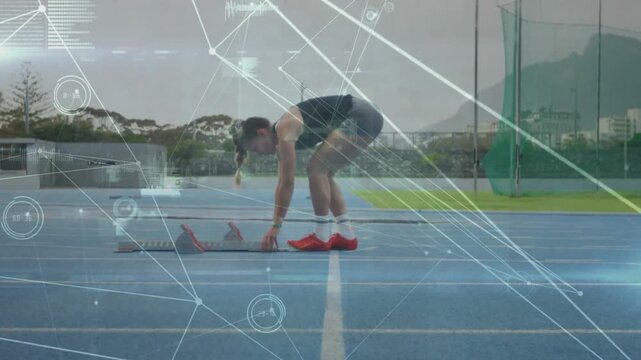 Preparing braided-hair female athlete wearing dark top adjusting starting blocks on blue track, HUD