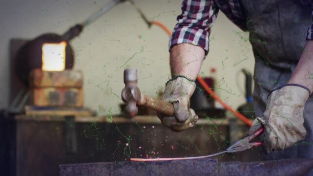 Male blacksmith gripping heated red-hot metal with tongs and hammering on anvil to flatten bar