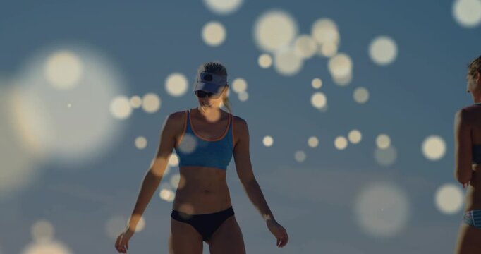 Two women playing sunny beach, after exchange woman walking toward camera showing visors for travel