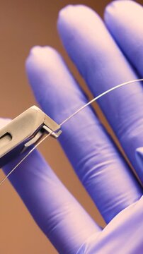 Extreme close up of orthodontist using pliers to handle thin archwire during braces adjustment. Gloved hands demonstrate precise control and careful fixation of orthodontic wire in clinical setting.