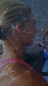 Vertical video: Woman pink top pushing arms in gym, sparking or fading net overlay visualizing fitne