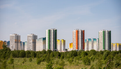 Fototapeta premium Colorful residential buildings rising above green trees in a modern cityscape in Zelenograd