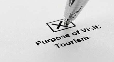 Pen marking checkbox for purpose of visit: tourism on paper  