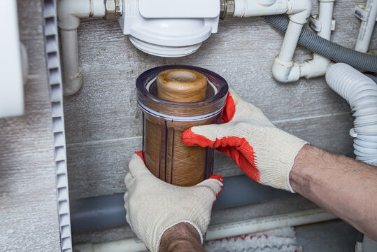 Hands in work gloves changing a water filter cartridge. Filters for water purification for plumbing pipes in a private house.