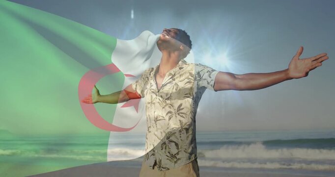 Travel man opening hands tilting head back beach, sun flare inspiring Algerian flag overlay at left