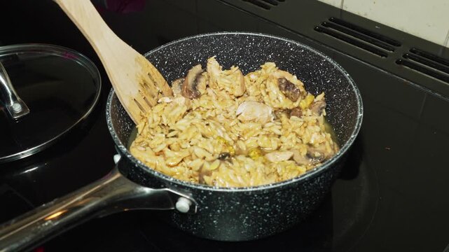 Close-up clip of cooking orzo, chicken and mushrooms in a saucepan