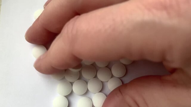 Many pills in the hand. A man takes a handful of white pills, suicide. Treatment for an illness.