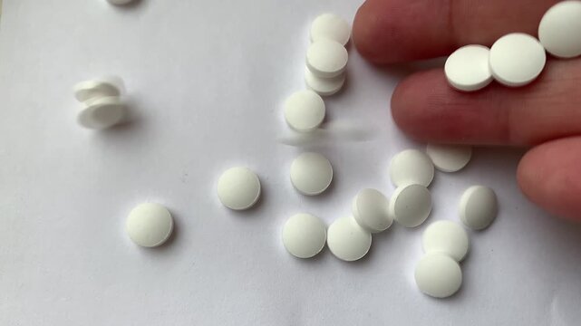 Many pills in the hand. A man takes a handful of white pills, suicide. Treatment for an illness.