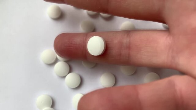 Many pills in the hand. A man takes a handful of white pills, suicide. Treatment for an illness.