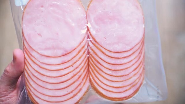 Canadian bacon deli slices, sliced meat pieces natural protein food hand holding macro closeup in plastic package bag