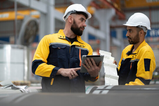 two professional engineer, worker, technician use clipboard discuss work, walk in steel metal manufacture factory plant industry. man and woman wear hard hat check quality machine. work, engineer.