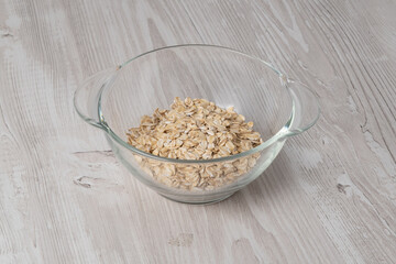 Bowl with dry oats placed on a wooden table ready for breakfast preparation