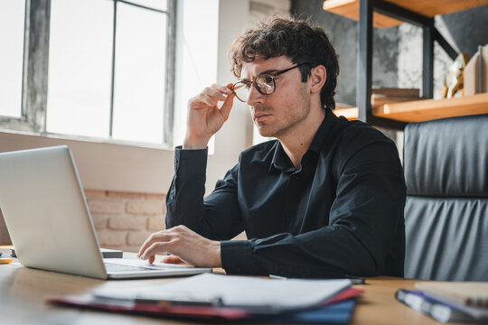 Worried, accountant and man with laptop in office, employee and mistake on financial report and web. Thinking, bookkeeper and male person with pressure for audit, research and anxious with tech