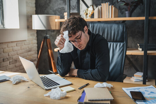 Man, tissue and sick by laptop in office with sneeze, allergy and virus infection on table. Business, health problem and male worker for cold, flu and fever symptoms in workplace for disease
