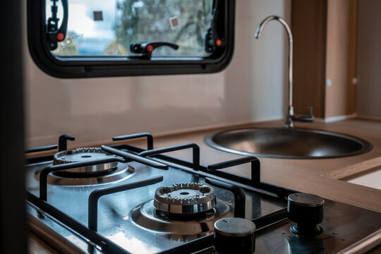 Modern camper van kitchen featuring a compact gas stove and round stainless steel sink, ideal for travel and van life