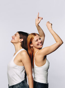 Two women dancing back to back and smiling in studio