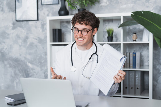 Online medical consultation. Confident male doctor family therapist sit by laptop talk to patient via telehealth videocall explain diagnosis give recommendations remotely from clinic office