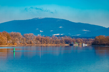 Fototapeta premium Winter landscape with reflections in river Danube and the Bavarian forest in the background on a sunny winter day at Stephansposching, Danube, Deggendorf, Bavaria, Germany