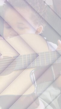 Vertical video: Baby reaching guitar on couch, dad guiding hands, teaching music, chevron overlay