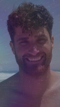 Vertical video: Man smiling laughing at ocean squinting in sun purple star overlaying for ads