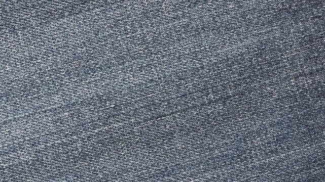 Soft fold gradually smoothing on worn blue denim fabric viewed from above. Minimal textile motion creating a clean jeans texture background for fashion, fabric or design concepts.