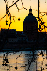 Obraz premium Silhouette of the dome of La Grave against an orange sunset sky in Toulouse, Occitanie, France