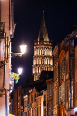 Fototapeta premium Bell tower of Saint-Sernin Basilica illuminated at night from Rue du Taur in Toulouse, Occitanie, France