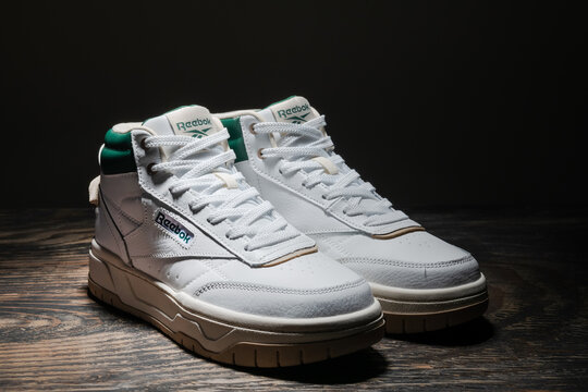 Reebok white high top sneakers on dark wooden surface