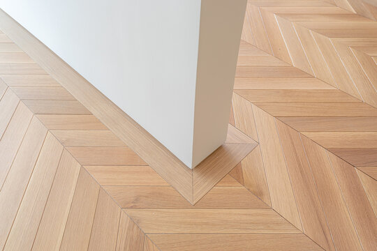 Minimalist interior architecture detail with herringbone wooden parquet floor pattern and clean white wall corner in modern apartment design