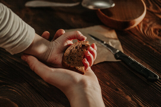 Child hands share bread with adult hands