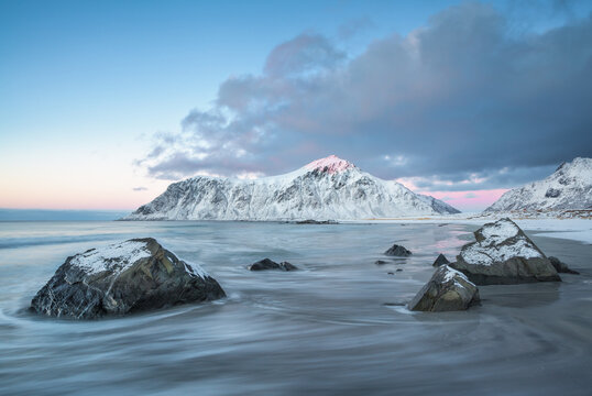 Pastel sunset developing over Skagsanden beach and snow covered mountains in winter, Flakstad, Lofoten, Lofoten and Vesteral Islands, Nordland, Norway