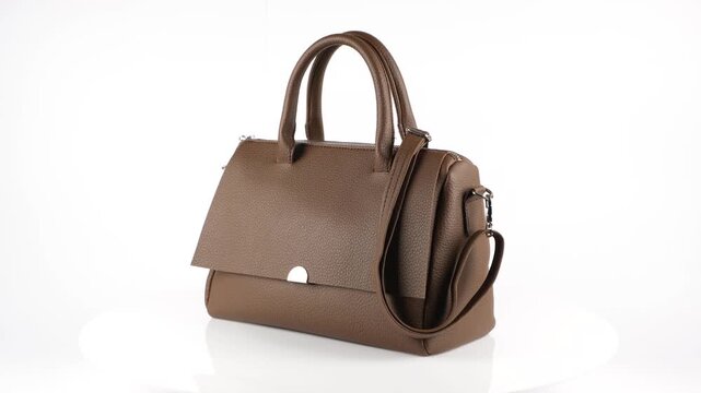 Seamless 360 degree rotation of an elegant brown leather women's handbag with top handle and shoulder strap. Studio product showcase in 4K resolution, ideal for fashion advertising, retail presentatio