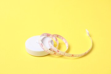 One measuring tape on yellow background, closeup