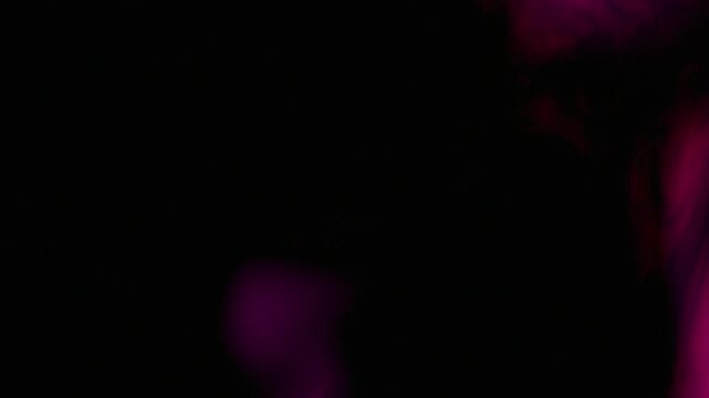 Pink magenta smoke clouds swirling in dark space environment. Abstract gaseous nebula effect with diffusion of vibrant colored fog. Dynamic flowing background texture.
