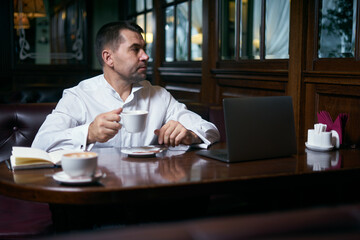 Businessman having coffee in a cafe while working on laptop