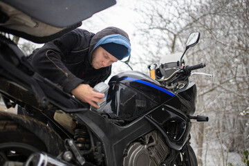 A man maintains a motorcycle in winter, motorcycle repair and maintenance